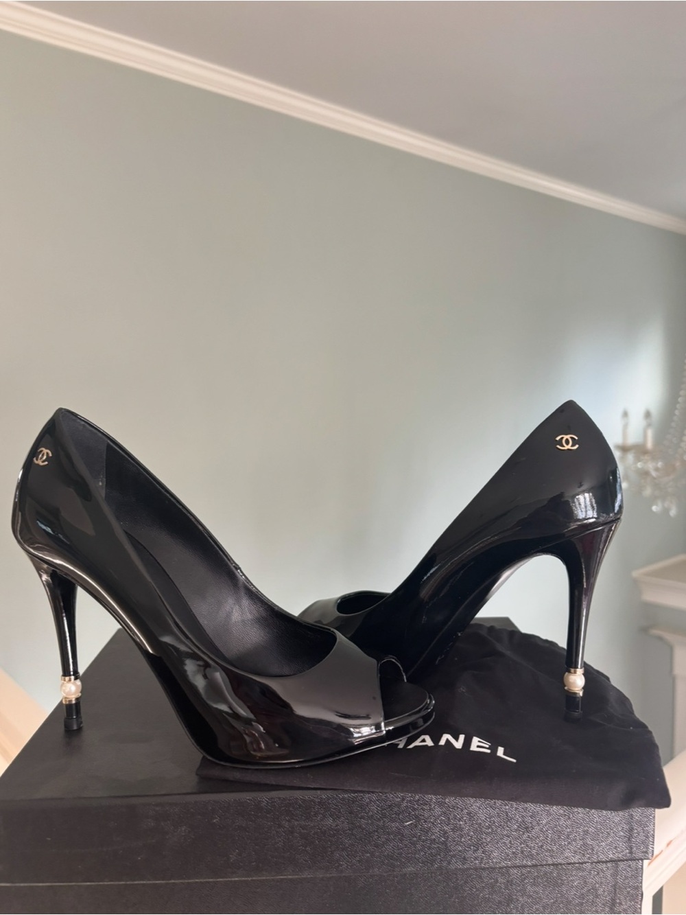 Black patent leather Chanel pumps with pearl detail.